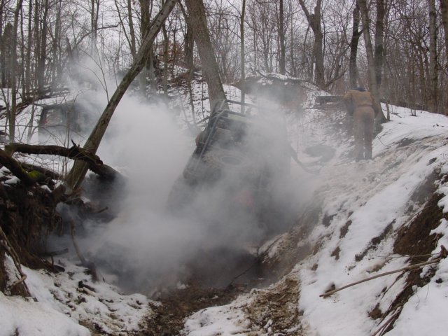 Off-road vehicle stuck in a snowy ditch, emitting smoke