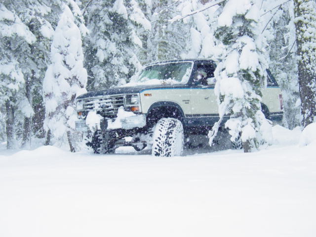 Ford Bronco driving through deep snow in a forest