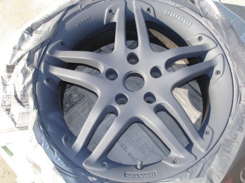 1989 Mazda MX-6 - A close-up view of a car wheel being painted, with newspaper used for masking.