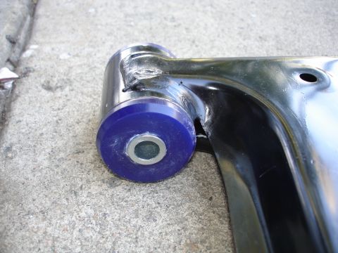1989 Mazda MX-6 - A close-up view of a suspension bushing, likely a performance upgrade part, against a concrete surface.