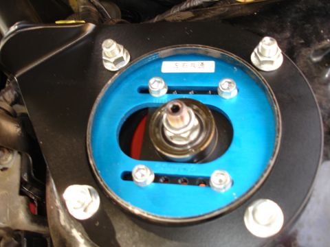 1989 Mazda MX-6 - Close-up of an adjustable front strut mount, a blue anodized top plate and visible Japanese text on a label.