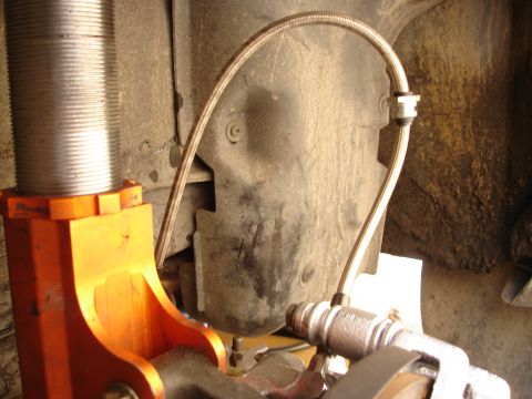 1989 Mazda MX-6 - Close-up of a vehicle's suspension and brake line, with visible text from SuperMotors.net.