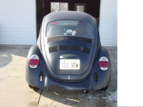 1975 Volkswagen Beetle - Rear view of a black Volkswagen Beetle with a skull sticker visible inside.