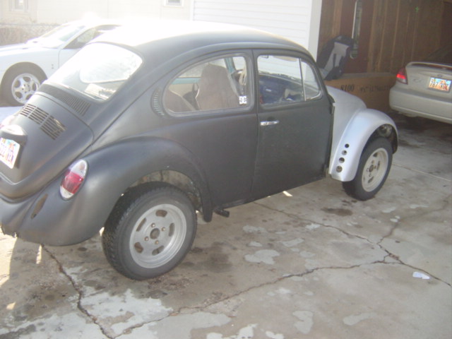 1975 Volkswagen Beetle with black body and silver front fender, parked outside