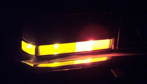 1985 Ford LTD Crown Victoria - The illuminated front marker lights and turn signal of a vehicle are visible in the dark.