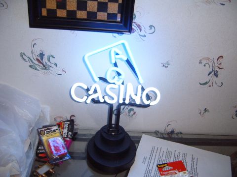 1988 Ford Bronco - A neon sign that reads "CASINO" is displayed against a patterned wallpaper, with a framed checkerboard artwork overhead.