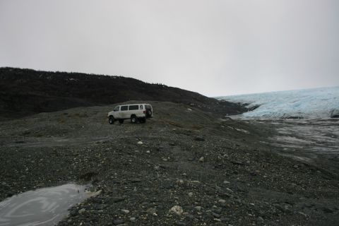 2003 Jeep TJ - A white van is parked on a desolate, rocky terrain near a large glacier under an overcast sky.