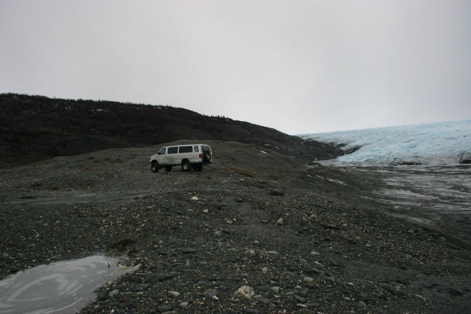 White van parked on a rocky, barren landscape with a glacier in the background