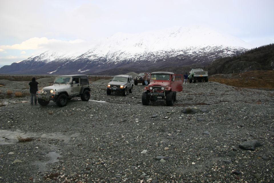 Red Toyota Land Cruiser FJ40 with a flatbed and a white Jeep TJ in a rocky, glacial landscape