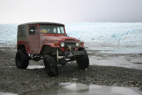 2003 Jeep TJ - A modified Toyota Land Cruiser FJ40 sits on a rocky beach with a vast glacier in the background.