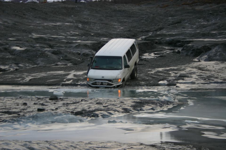 White van stuck in icy water on a rocky, barren landscape
