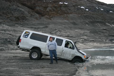 2003 Jeep TJ - White van with snorkel stuck in icy water on a gravelly slope.