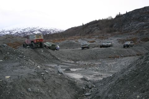 2003 Jeep TJ - A convoy of off-road vehicles navigates a , glacial landscape under an overcast sky.
