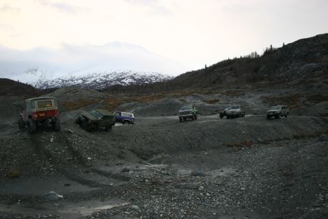 2003 Jeep TJ - A convoy of off-road vehicles navigates a desolate, rocky terrain with a , snow-covered mountain range in the distance.