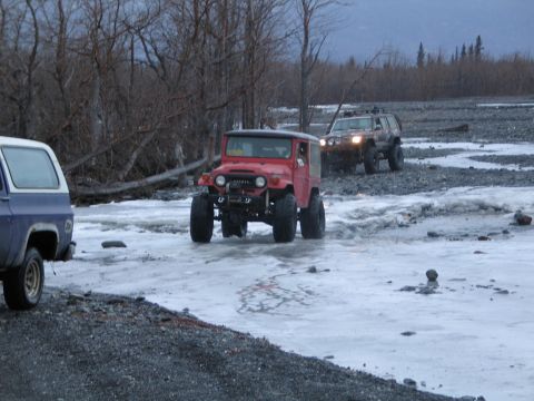 2003 Jeep TJ - Several off-road vehicles navigate a partially frozen, rocky landscape during winter.
