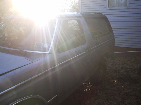 1981 Ford Bronco - The side profile of a 1981 Ford Bronco is visible, parked next to a house.