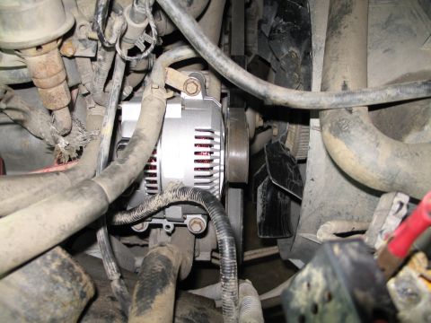1995 Ford Bronco - Close-up view of a vehicle's engine bay, focusing on the alternator and fan shroud.