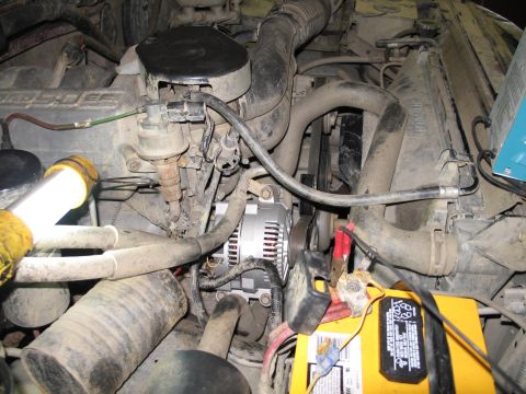 1995 Ford Bronco - Close-up of an engine bay, focusing on the alternator and battery during a potential swap or repair.