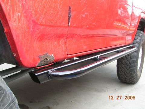 1985 Ford Bronco - Close-up of a red SUV's side, showing rust damage and aftermarket side steps.