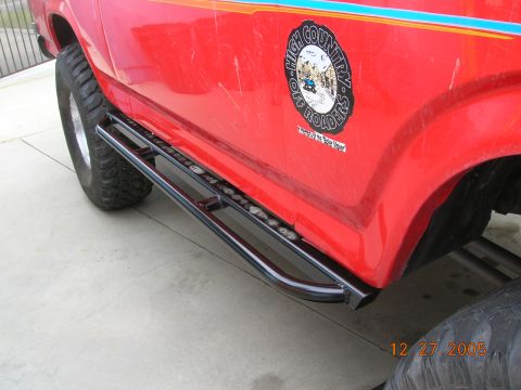 1985 Ford Bronco - A red SUV with off-road decals and side steps is shown from the side.