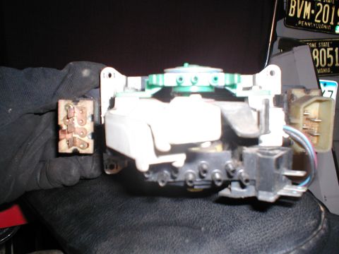 1979 Ford Bronco - A gloved hand holds a complex automotive electrical switch assembly, likely for a vehicle's interior controls.