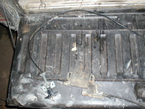 1979 Ford Bronco - Close-up of a tailgate latch mechanism and its associated cable, showing wear and dirt.