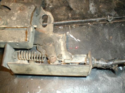 1979 Ford Bronco - Close-up of a vehicle's door latch mechanism, showing a spring and cable assembly.