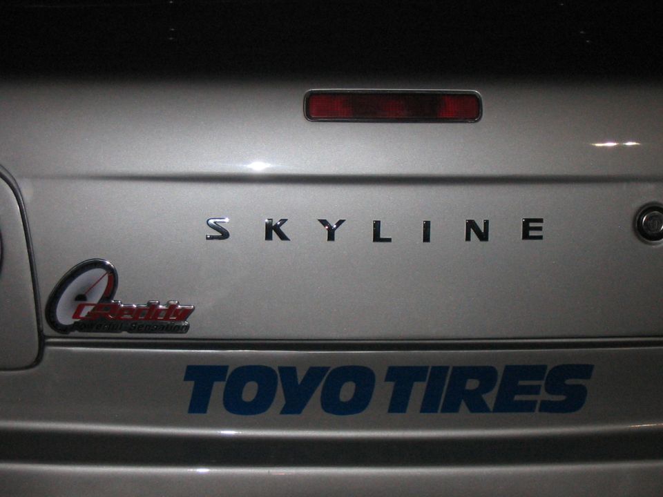 Silver car trunk with SKYLINE badging and TOYO TIRES sticker
