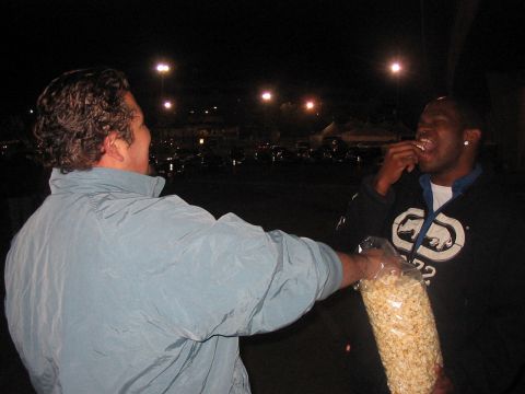 1986 Ford Bronco - Two men share a large bag of popcorn in a dimly lit outdoor setting at night.