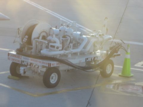 1968 Ford Mustang - A jet fuel cart with "JET A" visible on its side sits on an airport tarmac next to a traffic cone.