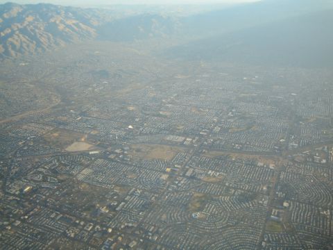 1968 Ford Mustang - An expansive cityscape stretches towards hazy mountains under a bright sky.