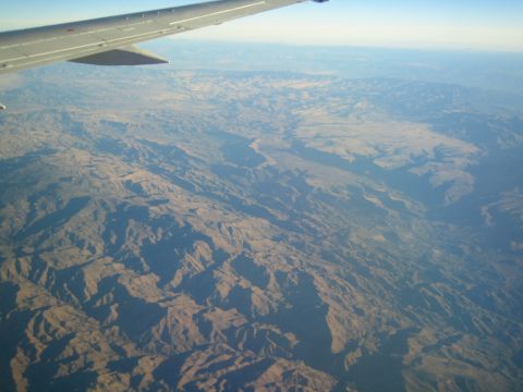 1968 Ford Mustang - View from an airplane window shows a vast, arid landscape with deep valleys and sharp ridges.