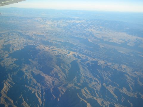 1968 Ford Mustang - An aerial perspective captures the vastness of mountainous terrain stretching towards the horizon under a pale sky.
