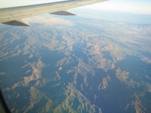1968 Ford Mustang - View from an airplane window shows an expansive mountainous terrain under a clear sky.