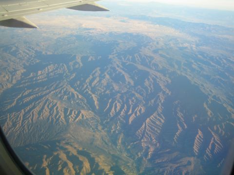 1968 Ford Mustang - An aerial view shows a vast, mountain range under a hazy sky, seen from a plane.