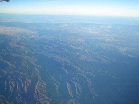 1968 Ford Mustang - An expansive aerial view captures the vastness of mountainous terrain under a bright, clear sky.