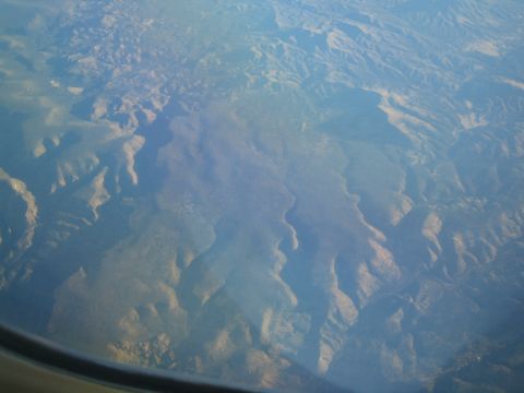 1968 Ford Mustang - View from an airplane window shows a vast expanse of mountains and valleys under a hazy sky.
