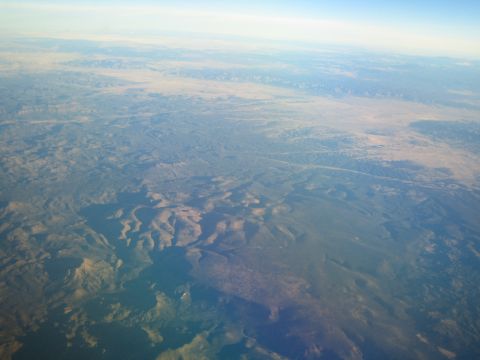 1968 Ford Mustang - An aerial view captures the vastness of a mountainous landscape under a pale blue sky.