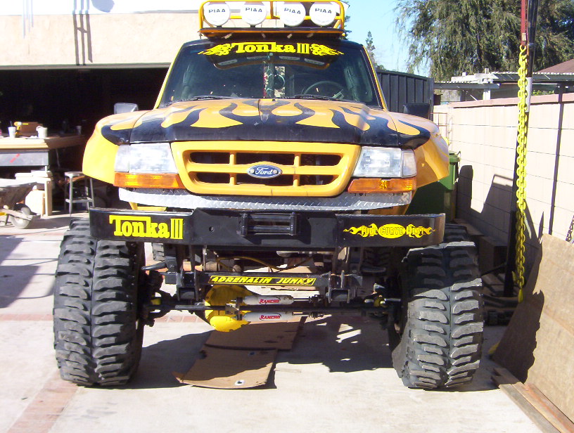 Front view of lifted yellow Ford Tonka III pickup with flames, PIAA light bar and mud tires