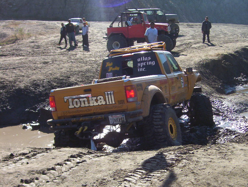 Yellow Tonka III pickup in a muddy rut, rear three-quarter view