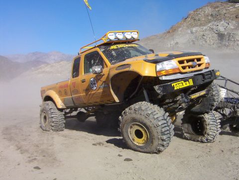 2000 Ford F-450 - Dusty three-quarter front view of a yellow Ford Ranger extended-cab rock crawler with a black hood scoop panel, 'TONKA' lettering on the wi…