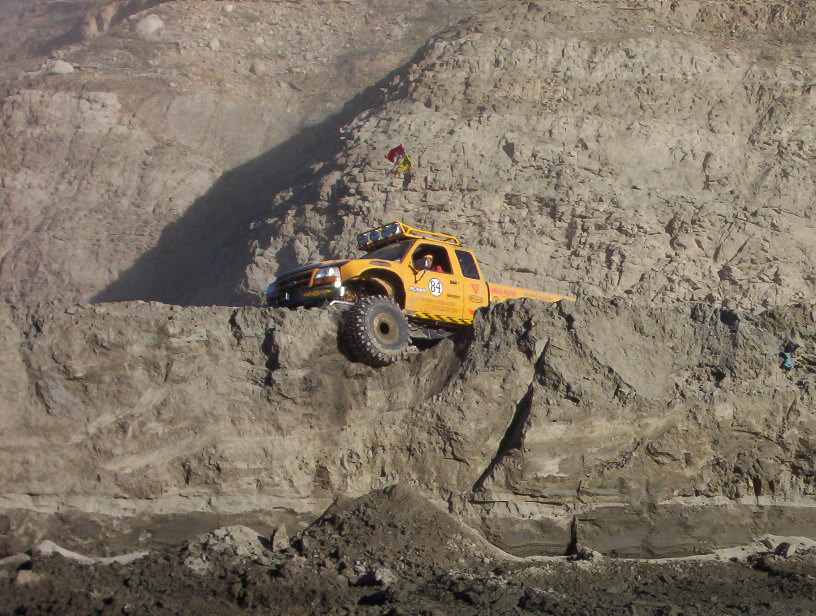 Yellow number 84 off-road pickup on a ledge high on a quarry wall