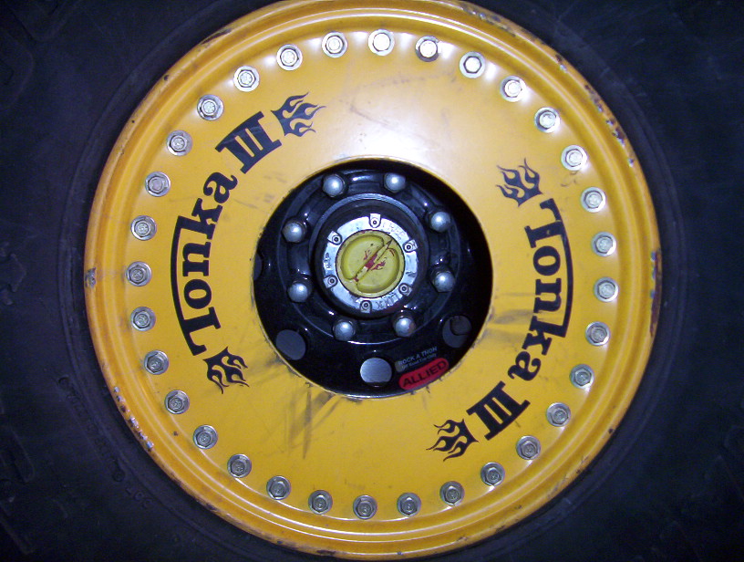 Yellow dually wheel with black Tonka III flame lettering and chrome lug nut covers