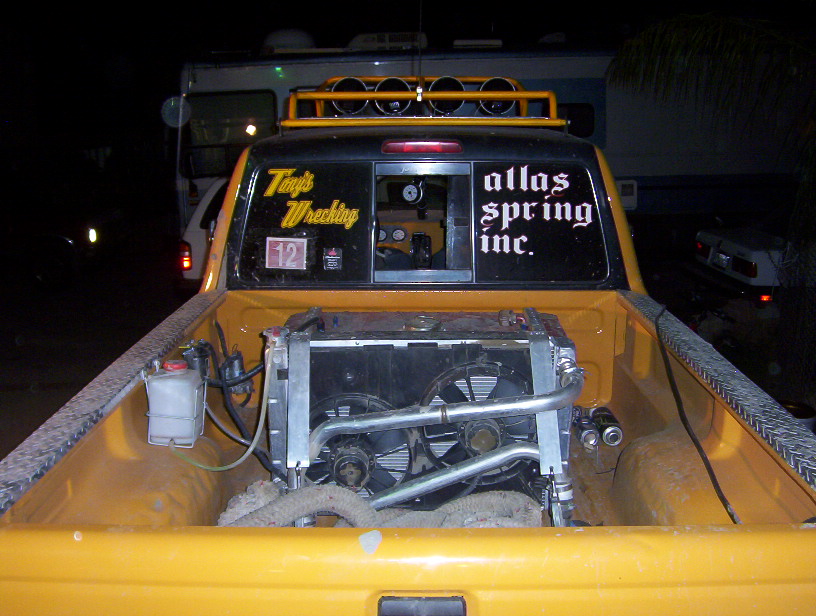 Radiator and twin-fan module loaded in the bed of a yellow pickup at night