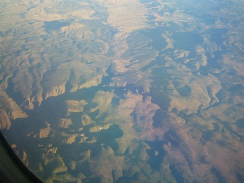1968 Ford Mustang - View from airplane window shows a large canyon system with geological formations and arid vegetation.