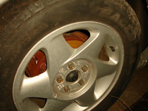 1992 Ford Taurus - A close-up view of a vehicle's wheel, showing the tire, alloy rim, and brake components.