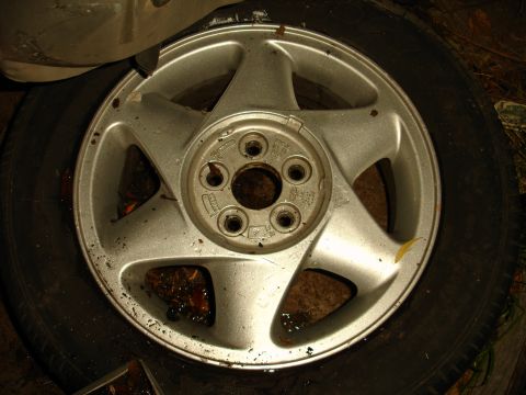 1992 Ford Taurus - A close-up view of a dirty alloy wheel and tire, showing its five-spoke design.