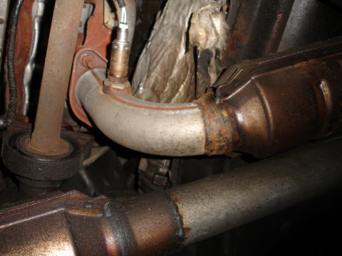 1992 Ford Taurus - Underside view of vehicle exhaust components, including a catalytic converter and an oxygen sensor.