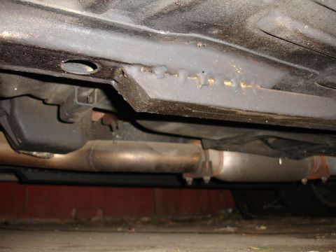 1992 Ford Taurus - Close-up of car's undercarriage, showing subframe connectors and exhaust system components.