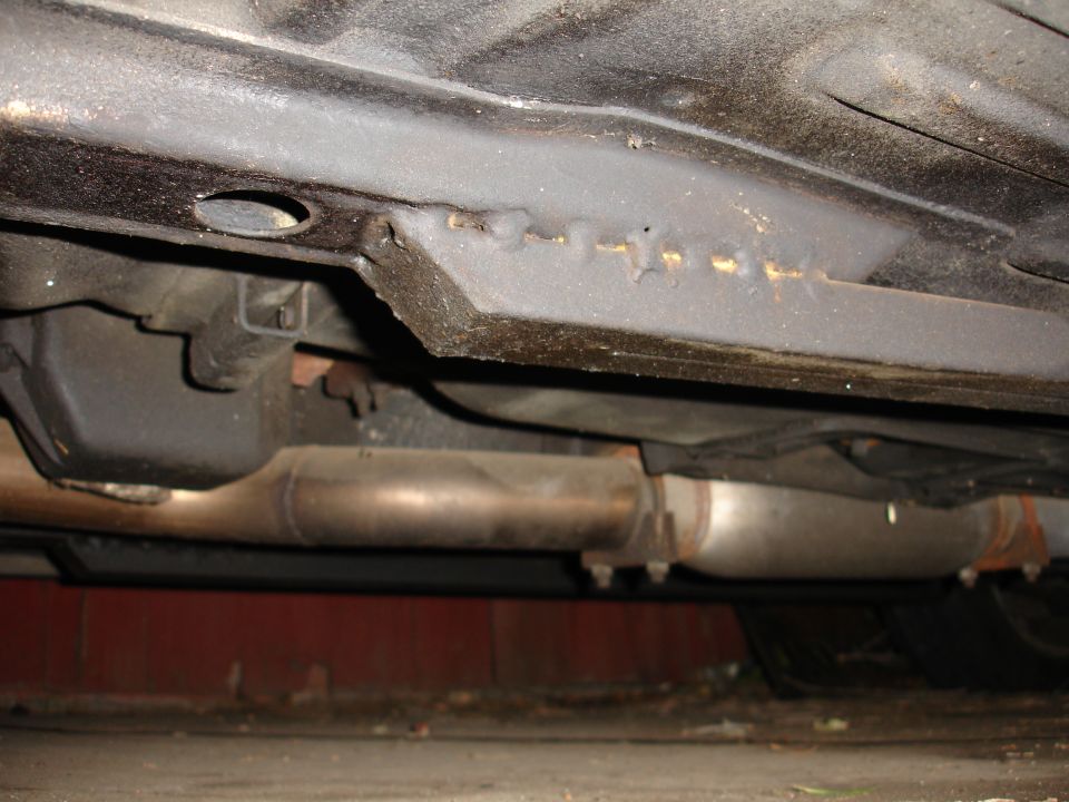 Underside of a car showing subframe rail, spot welds and exhaust resonator